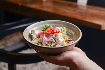 Waiter, carrying a plate with rich salad. Vegetable salad with mayonnaise. Eating out in restaurant, restaurant service