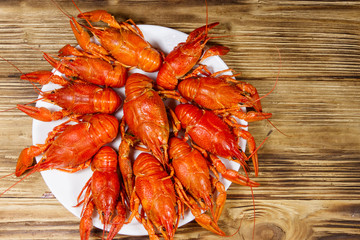Boiled crayfish in plate on wooden table. Top view