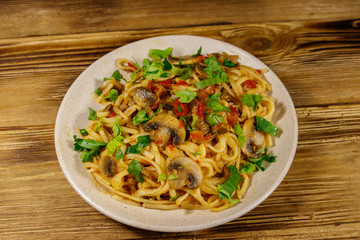 Pasta with mushrooms and tomato sauce on wooden table