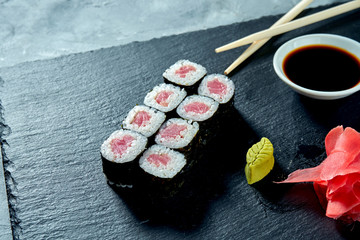 Appetizing maki sushi with tuna on a black slate board