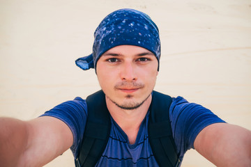 male Caucasian tourist wearing a bandana makes a selfie at camera