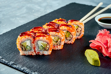California sushi roll in tobiko caviar with eel and philadelphia cheese on a black slate board. Selective focus
