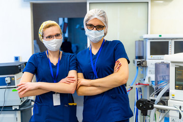 Fototapeta na wymiar Two nurses in masks standing cross hands on medical equipment background. Lungs ventillation equipment.