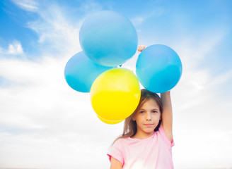 Fototapeta na wymiar girl holding balloons of blue and yellow colors in her hands