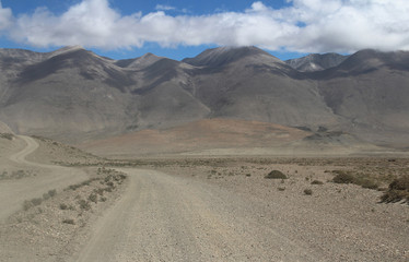 Fototapeta na wymiar View of the mountain and sand dune with dirt road in a sunny day, Tibet, China