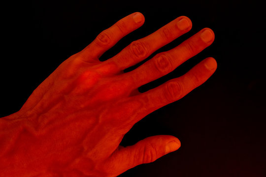 Abstract background of red illuminated hand on black background. Main object full of noise