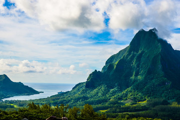 Moorea, French Polynesia: 09/03/2018: Total lanscape of the colorful main mountain in Moorea, everywhere is green and a blue sky