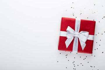 Fototapeta premium Gift or present box and stars confetti on color table top view. Flat lay composition for birthday, mother day or wedding.