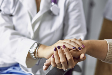 Obraz premium Woman doctor calms patient and holds hand