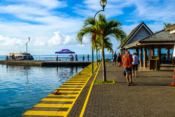 Moorea, French Polynesia: 09/03/2018: People walking on the street next to the ocean in a summer day in Moorea