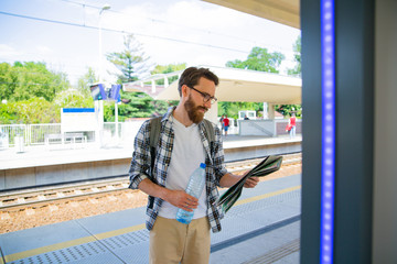 Tourist, urban traveller looking at the map on a railway station platform.