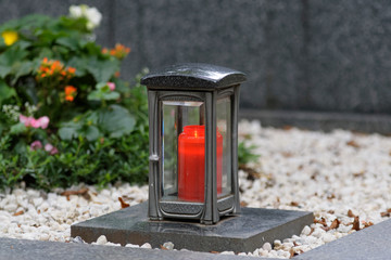 metal  death lantern with glass plates and a burning red candle on a gravestone
