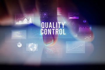 Finger touching tablet with charts and QUALITY CONTROL inscription, business concept