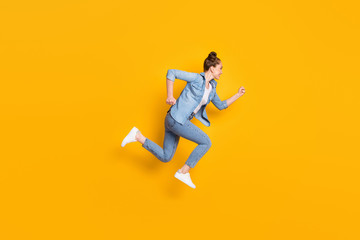 Fototapeta na wymiar Full body profile photo of attractive teen lady jumping high up running race marathon excited to win rushing wear casual denim shirt sneakers pants isolated yellow color background