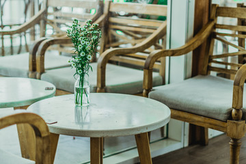 Fototapeta na wymiar Furniture decoration in empty on people cafe bar restaurant retro modern style during second wave quarantine city lockdown. Wood table chair glass vase chamomile. Coffee shop interior design