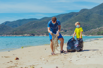 Volunteers blue face mask paradise beach sand lazur sea. Father son pick up garbage into black bag....