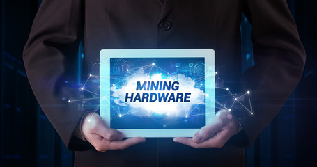 Young business person working on tablet and shows the inscription: MINING HARDWARE
