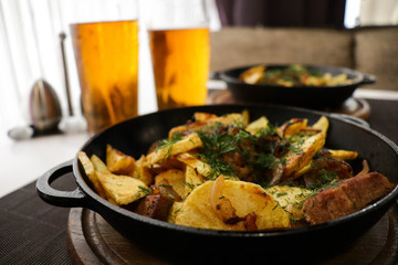 meat with potatoes and vegetables cooked in a pan and glasses with beer