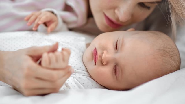 Mother singing lullaby to asleep cute baby relaxing together. Medium close up shot on 4k RED camera