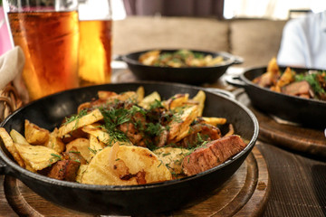 meat with potatoes and vegetables cooked in a pan and glasses with beer