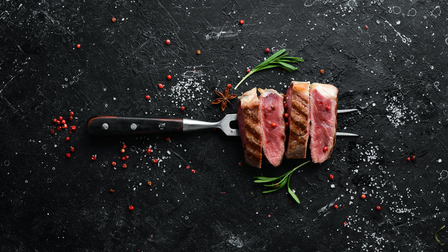 Grilled ribeye beef steak on the fork. Top view. Free space for your text.