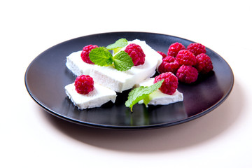 Ice cream with raspberries and mint on a black plate, white background