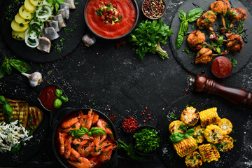 Set meal of meat, seafood and vegetables on the black stone table. Top view. Free space for your text.