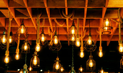 Close up many yellow lamp in cafe at night. Hang from wood ceiling