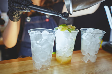 Bartender making mojito cocktail. Process of bartending in bar.Mint leaves,ice,lime - ingredients for drinks in nightclub.Blurred image, selective focus