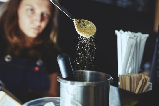Bartender wearing medical latex black gloves,making mojito cocktail.Process of bartending in bar,pouring a tablespoon of brown sugar in shaker.Blurred image, selective focus
