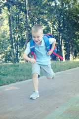 Fototapeta na wymiar boy with a backpack running in the park. Education childhood concept