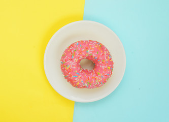 Fototapeta na wymiar Top view,One pink glazed donut on white plate on pastel yellow turquoise background
