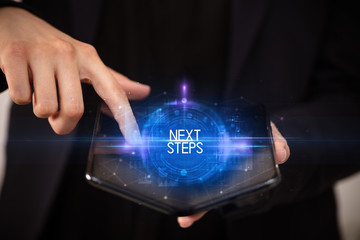 Young man holding a foldable smartphone with NEXT STEPS inscription, educational concept