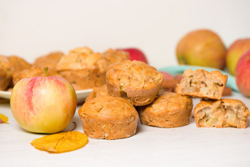 homemade Apple cupcakes and muffins, light background, yellow leaves. the concept of fall baking and fall harvest. cupcake is broken into pieces, filling with Apple