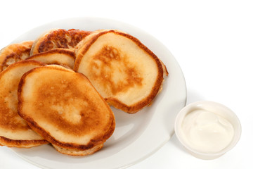Several pancakes on a plate and a little sour cream on a white background. Full depth of field. With clipping path.