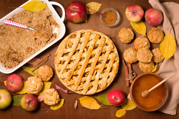 autumn baking concept with seasonal apples and cinnamon. Apple pie, crumble, crisp, and muffins, cupcakes . top view on a wooden background with autumn yellow leaves.