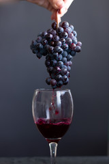 Pouring red wine into the glass from the grapes