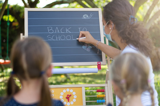 Back To School. Back To School Written On Classroom Chalkboard By Teacher With Face Mask. Outdoor Classroom Due To Covid-19.