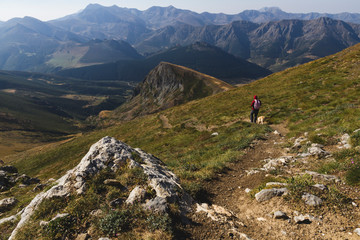 Man climbing to the top of a mountain Coriscao with a dog in Leon on a sunny day, Spain