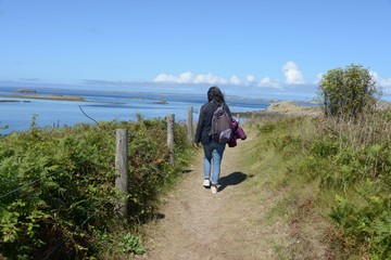 Obraz premium Femme de dos marchant sur un sentier littoral sur l'île de Molène en Bretagne.