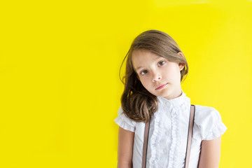 serious pretty schoolgirl. cute caucasian girl with blond hair on yellow background. The concept back to school. Copy space