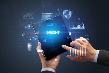 Businessman holding a foldable smartphone with INSIGHT inscription, successful business concept