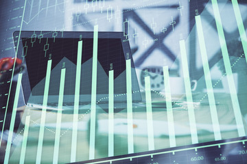 Stock market graph on background with desk and personal computer. Double exposure. Concept of financial analysis.