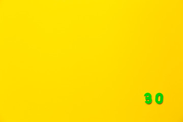 A green plastic toy number thirty is located in the lower right corner on a yellow background