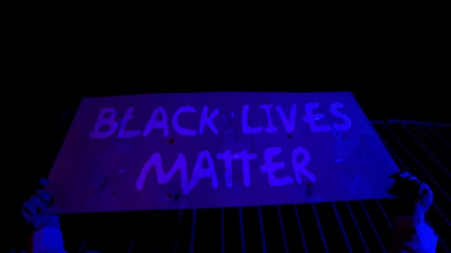 The crowd protests against racial inequality. Riot against police brutality and racism. Red and blue Light police car. Black Rights Protest
