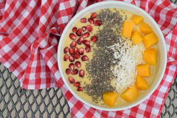 Mango smoothie bowl with coconut , pomegranate and chia seeds
