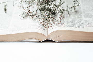 Open old book with field flowers on it. Photo