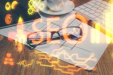 SEO hologram with glasses on the table background. Concept of search engine optimization. Double exposure.