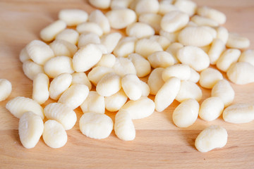 Traditional gnocchi, handmade italian pasta, with tomatoes on wooden table, natural light