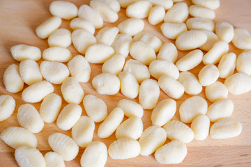 Traditional gnocchi, handmade italian pasta, with tomatoes on wooden table, natural light